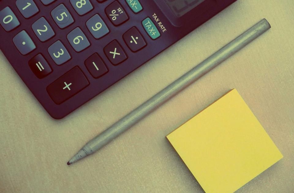 Calculadora e anotações sobre uma mesa de trabalho