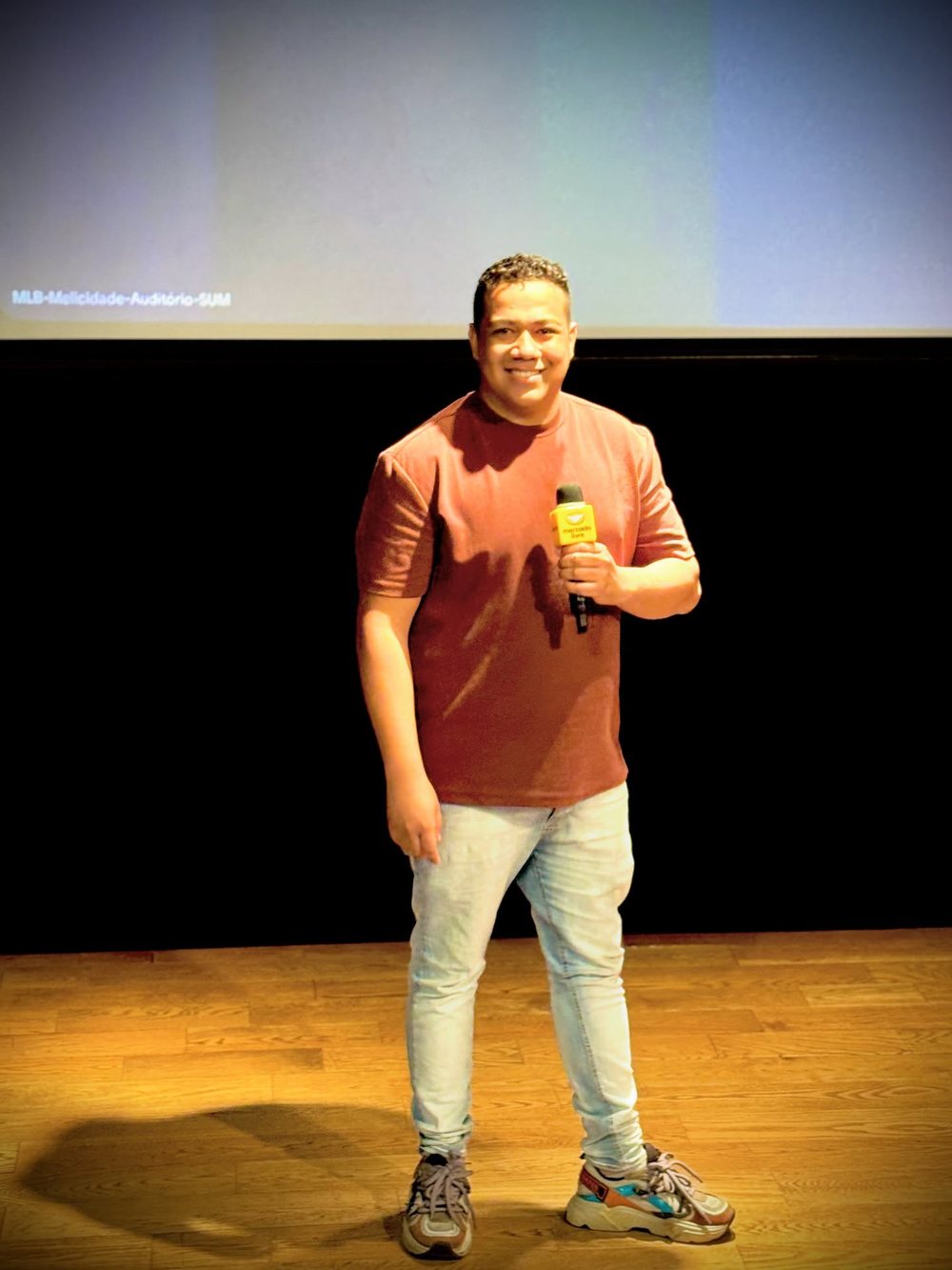 Kleitom Mendes no palco do auditório do Melicidade, sede do Mercado Livre, com o microfone da plataforma